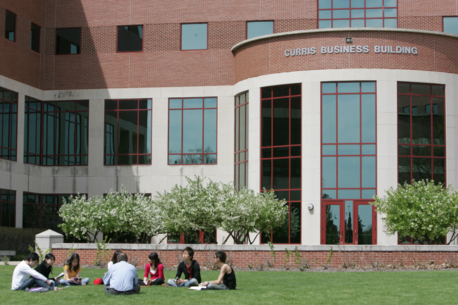 Students sitting together outside of Curris Business Building